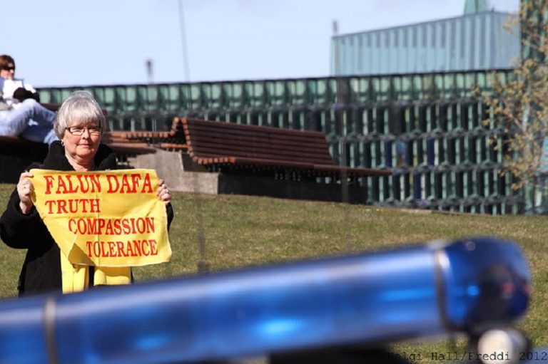 A Falun Gong (Falun Dafa) practitioner in Iceland protests the arrival of a high-level Chinese official in 2012. The small banner she holds includes the practice’s three core principles: Truthfulness, Compassion, and Tolerance. (Image: Wikimedia)
