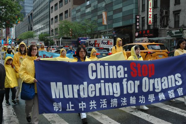 Falun Gong practitioners taking part in a Manhattan parade on May 11, 2024 hold a banner calling attention to the crime of forced organ harvesting by the Chinese regime. (Image: Ila Bonczek/Vision Times)