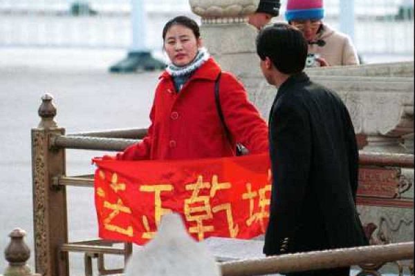 A Falun Gong practitioner holds up a banner saying “Truthfulness, Compassion, Tolerance” during a protest in China in the early 2000s. (Image: Minghui.org)